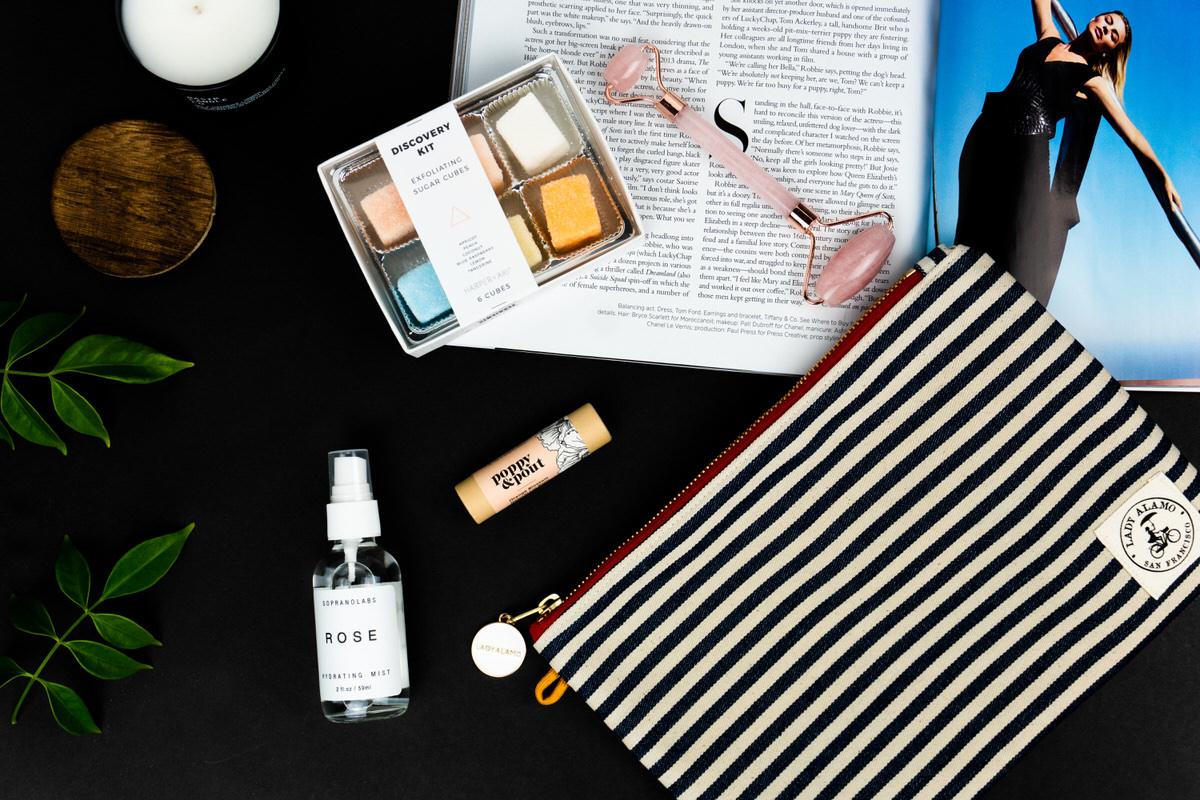 Rose mist, lip balm, sugar cubes, and a rose quartz roller on an open magazine