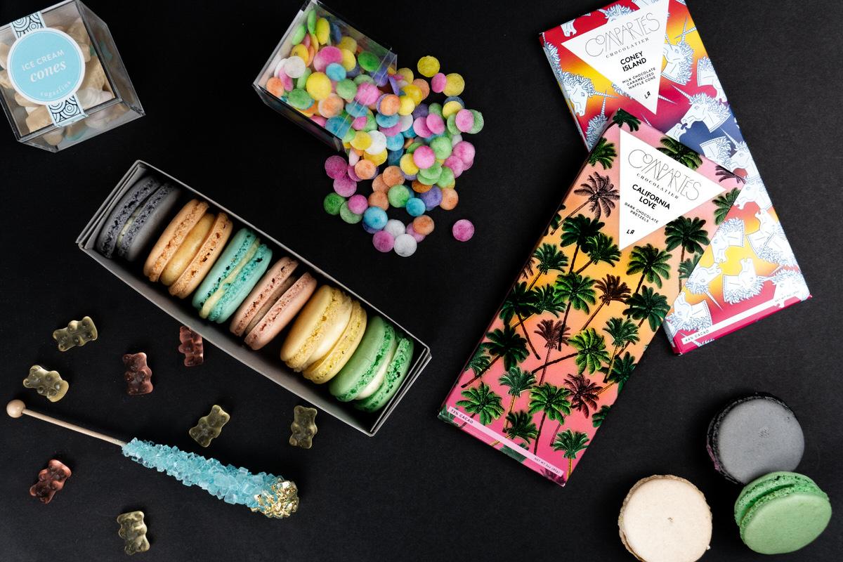Macarons, gummy bears, and chocolate bars laid out on black